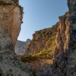 Gola abruzzese con pareti rocciose e vegetazione lussureggiante, panorama mozzafiato.