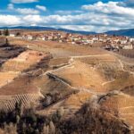 Panorama mozzafiato di un paese piemontese con colline e vigneti.