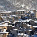 Borgo italiano tranquillo con tavoli all'aperto, persone che pranzano lentamente immersi nella natura.